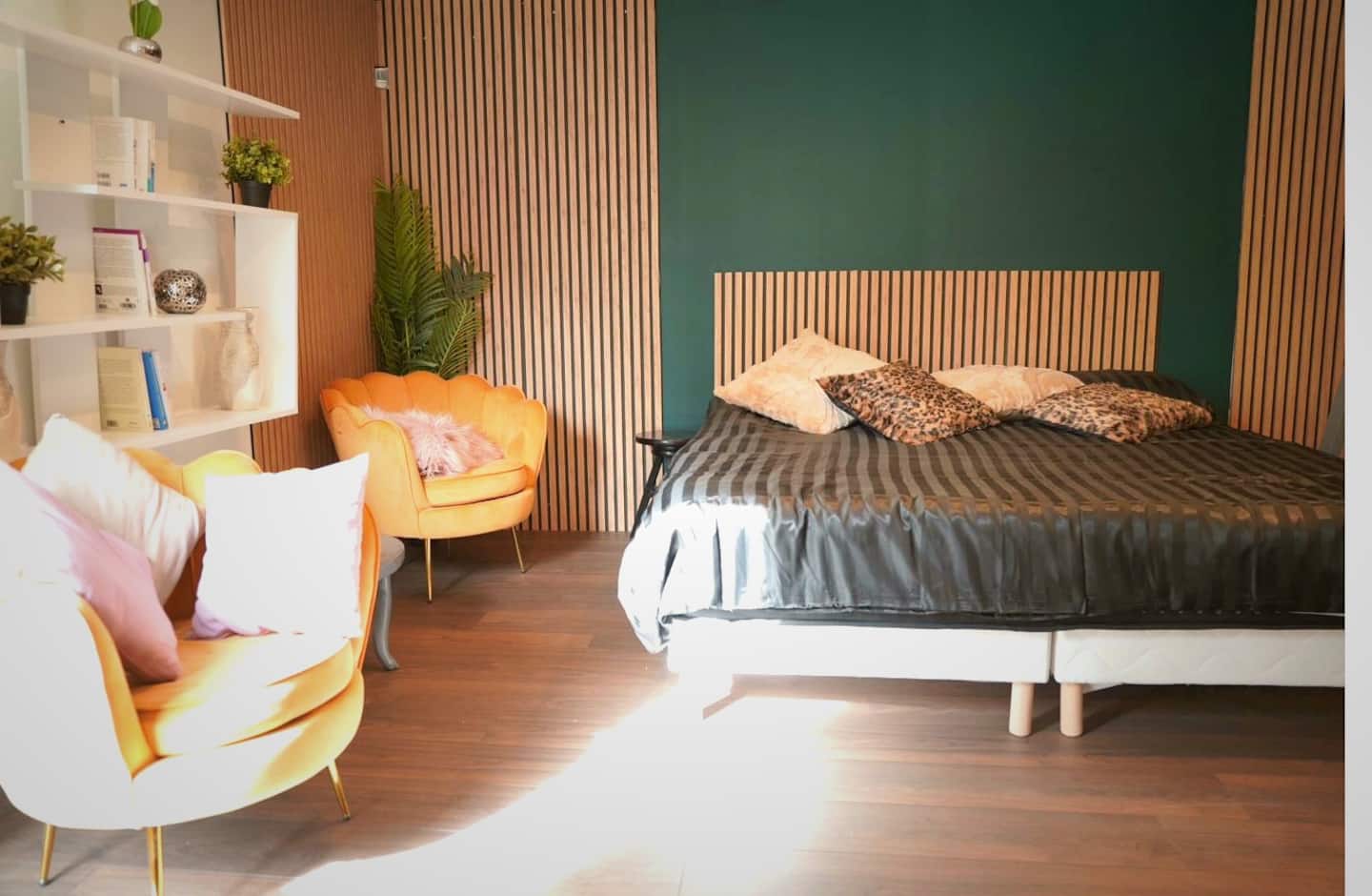 La chambre privée avec son lit double, son coin salon et son mur en tasseaux de bois